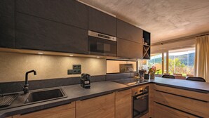 Una cucina moderna con mobili scuri, forno integrato e un'ampia finestra con vista sull'esterno.