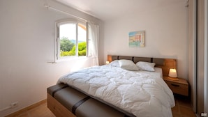Una camera da letto con un letto, un comodino, una finestra e un quadro appeso al muro.
