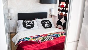 Una cama bien hecha con un edredón colorido y dos almohadas con citas motivacionales.