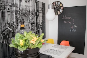 Una habitación con una pizarra que muestra 'Welcome home!' y una planta en maceta sobre una mesa.