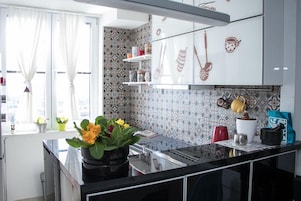 Una cocina moderna con salpicadero estampado, armarios blancos y encimera negra.