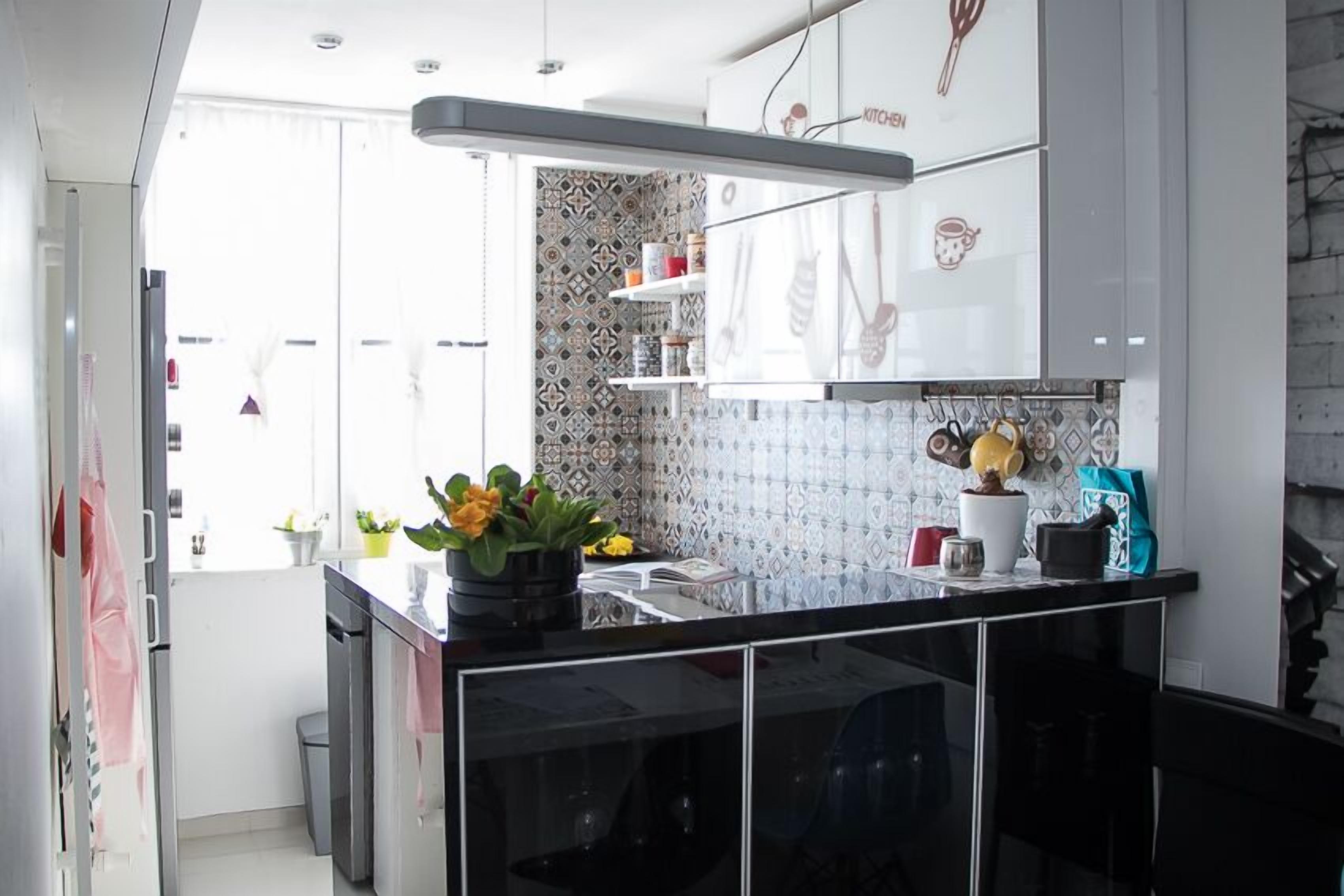 Una cocina moderna con encimeras negras, armarios blancos y un salpicadero con azulejos estampados.