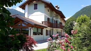 A two-story house with a balcony, surrounded by lush greenery and mountains. - Green Rose bed and breakfast (Cesiomaggiore)