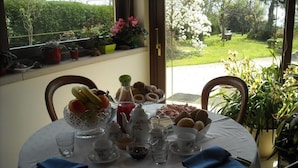 A round dining table set with a white tablecloth, various dishes, and drinks. - Green Rose bed and breakfast (Cesiomaggiore)