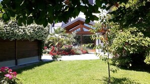 A garden with a wooden fence, a lawn, and a building with a sloped roof. - Green Rose bed and breakfast (Cesiomaggiore)