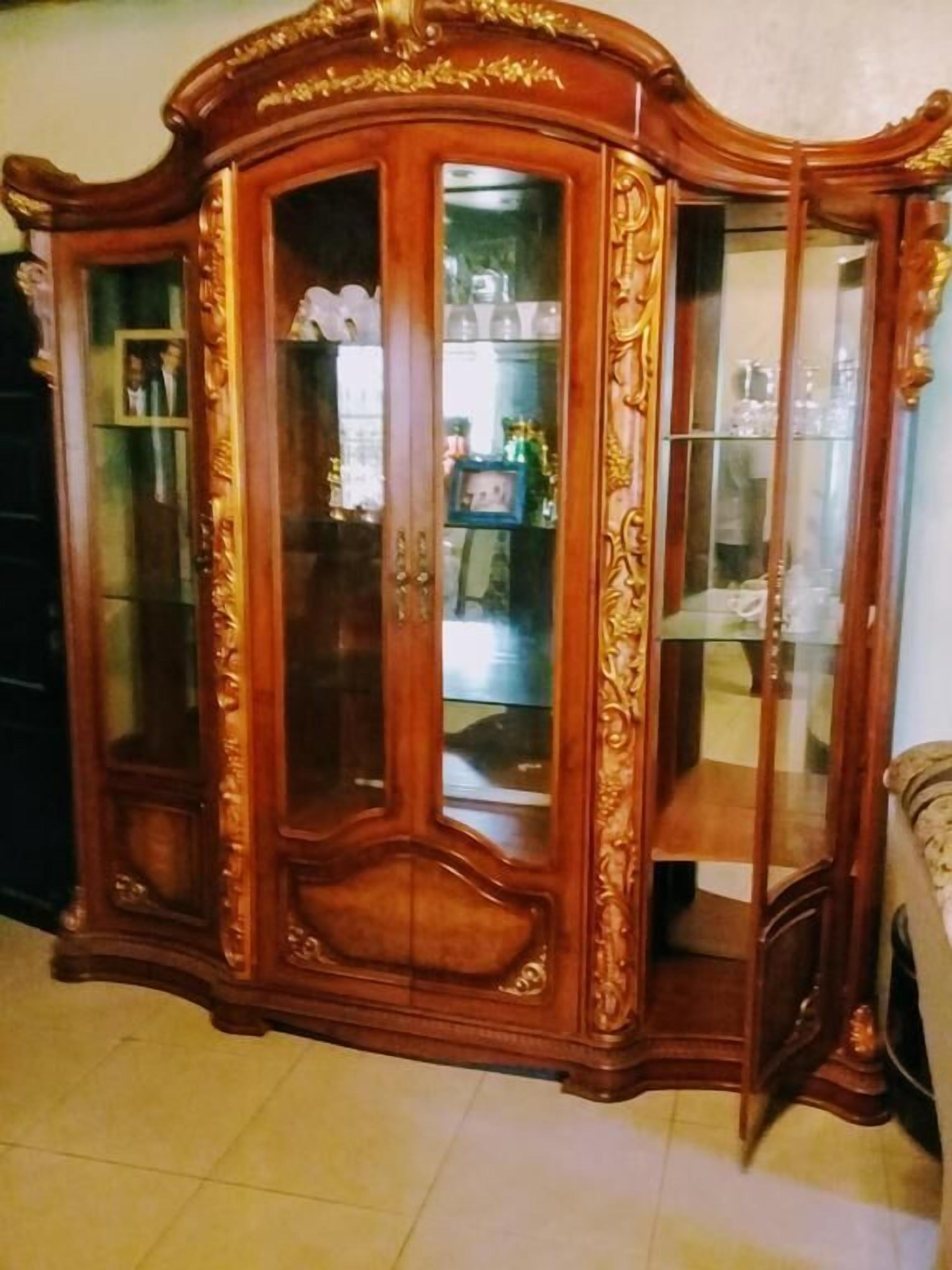 A large wooden cabinet with glass doors, featuring intricate carvings and a classic design.