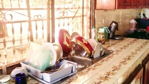 Una cocina con salpicadero de azulejos, armarios de madera y una ventana con celosía decorativa de metal.