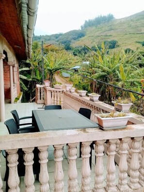 An outdoor dining area with a table and chairs, surrounded by a balustrade and potted plants. - Maisons D'Hotes Laguiri (Maoueni)