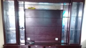 Una habitación con un armario grande de madera con puertas de cristal, una alfombra estampada y un pequeño sofá.