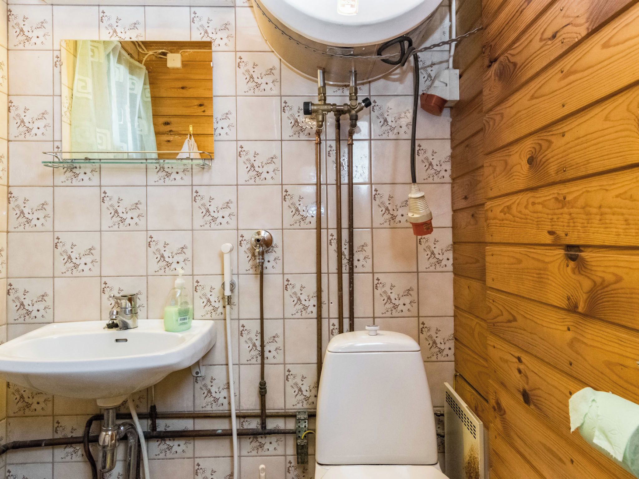 Een badkamer met een houten wand, een toilet, een wastafel en een douche.