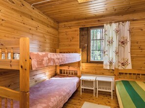 Una cabaña con literas, una mesita y un ventanal con cortinas.