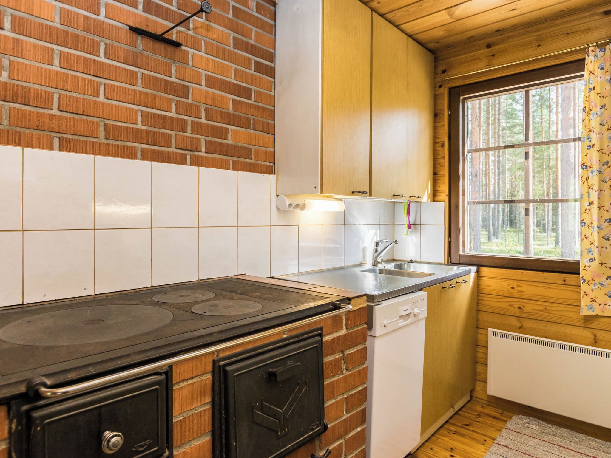 Une cuisine de taille réduite, équipée d’une cuisinière, d’un évier et de meubles de rangement en bois.