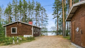 A rustic cabin with a dirt path leading to a lake, surrounded by tall pine trees. - Mäntyniemi by Interhome (Mäntyharju)