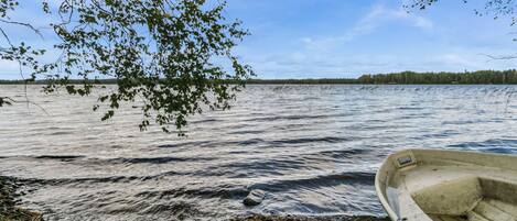 Um lago tranquilo com um barco na margem e um galho de árvore pendurado sobre a água.