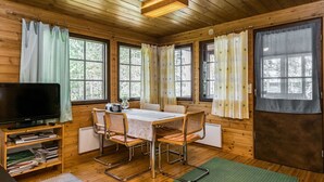 A cozy cabin with a wooden interior, a dining table with chairs, a television, and a bookshelf. - Mäntyniemi by Interhome (Mäntyharju)