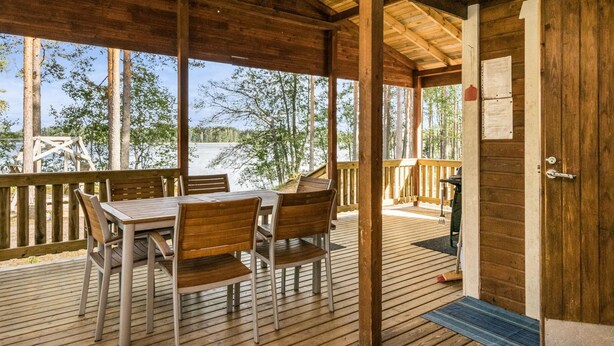 A wooden deck with a table and chairs, overlooking a lake. - Mäntyniemi by Interhome (Mäntyharju)