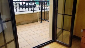 Une pièce dotée d’une porte-fenêtre coulissante donnant sur un balcon carrelé et muni d’une rambarde en métal.