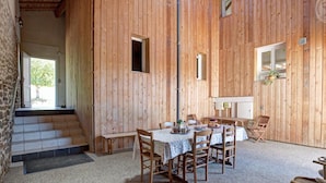 A rustic wooden interior with a dining area, a staircase, and a small kitchen area.