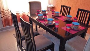 A dining table set with multiple bowls and plates, surrounded by chairs. - Muthama Heights (Syokimau)