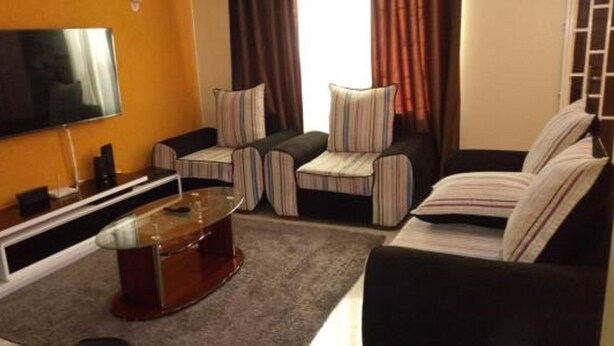A living room with a flat-screen TV, a coffee table, striped armchairs, and a sofa. - Muthama Heights (Syokimau)