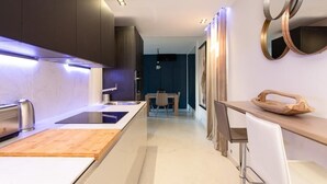 Une cuisine moderne dotée d’un îlot central, de meubles de couleur sombre et d’un coin repas avec une table et des chaises.