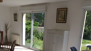 En rummelig stue med en stor skydedør til en have, et spiseområde med bord og stole, samt et hvidt skab.
