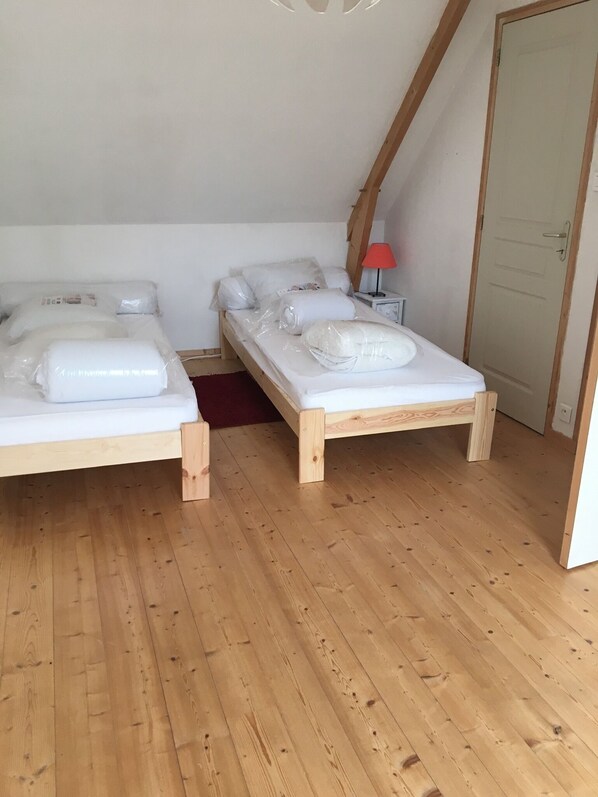Ein Zimmer mit zwei hölzernen Betten, einer roten Lampe und einer weißen Tür.