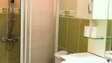 Un baño con ducha, inodoro, lavabo y armario.