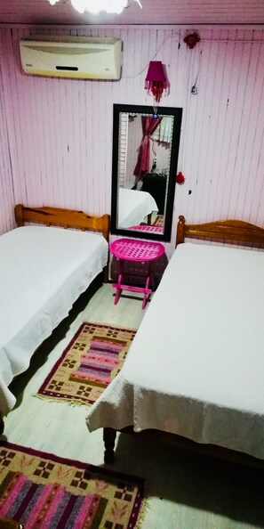 A room with two single beds, a small pink stool, a mirror, and an air conditioning unit. - Side Erenler Hotel (Manavgat)