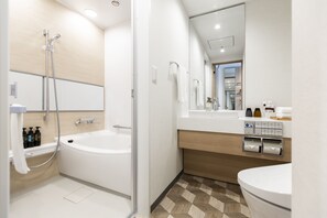 Ein modernes Badezimmer mit einer Badewanne, einer Toilette, einem Waschbecken mit Spiegel und einer Dusche.