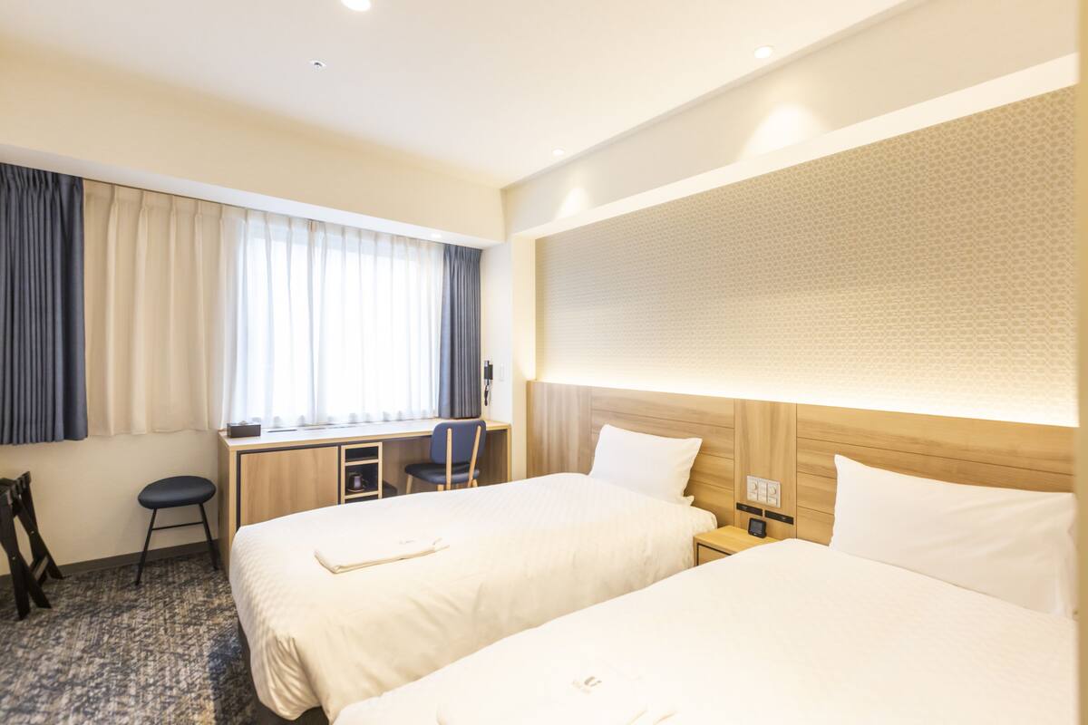 Una habitación de hotel con dos camas, un escritorio y una silla.