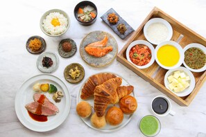 Eine Auswahl an Speisen, darunter Reis, Fisch und Brot, auf einer Tablett und Tellern angerichtet.
