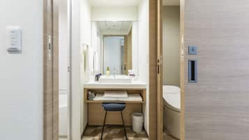 A modern bathroom with a white sink, mirror, and toilet. There is a towel rack and a trash bin. The floor has a geometric tile pattern.