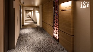 Een hotelgang met een tapijten vloer, houten wanden en een decoratieve glazen wand.