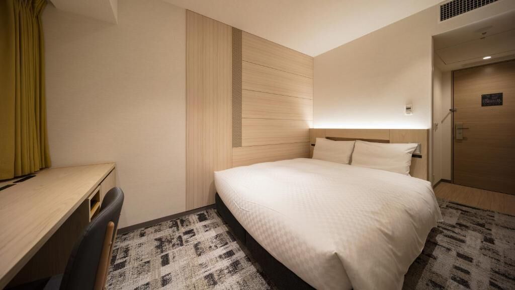 A hotel room with a bed, a desk, and a chair.