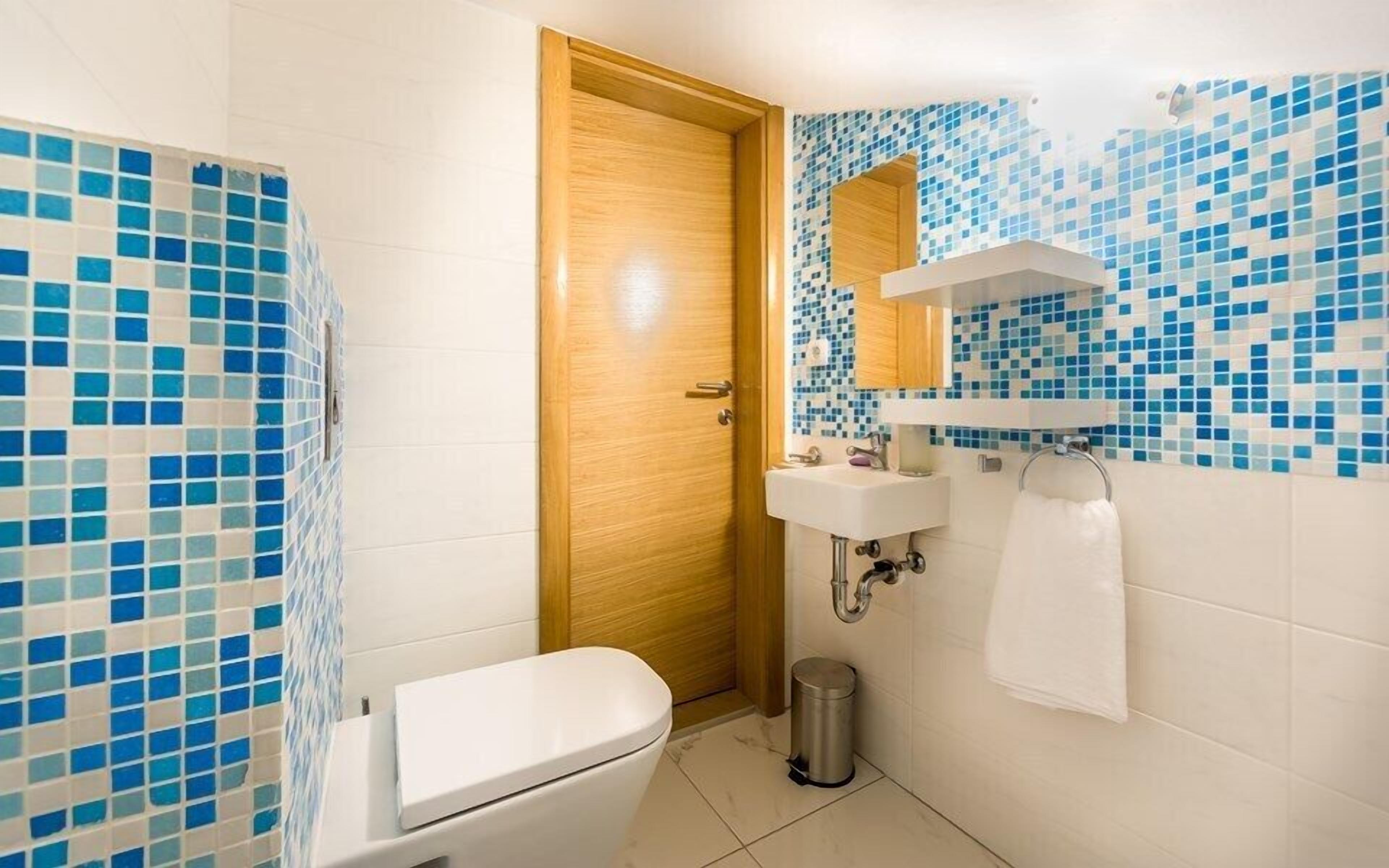 A bathroom with a toilet, sink, and mirror.