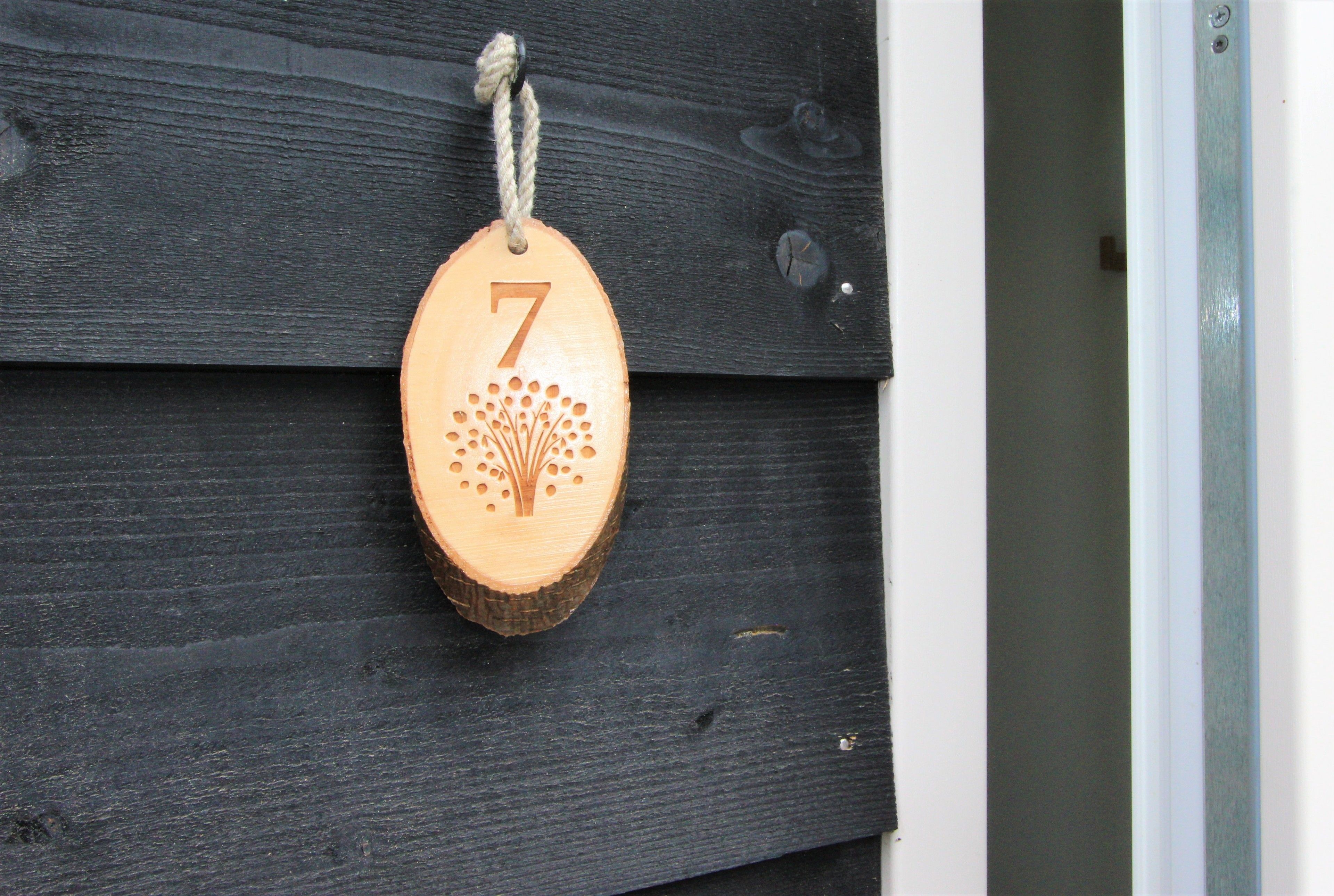 A wooden number plaque with the number 7, hanging on a dark wooden wall.