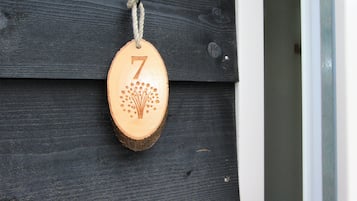 Een houten naambordje met het getal 7, hangend aan een donkere houten wand.