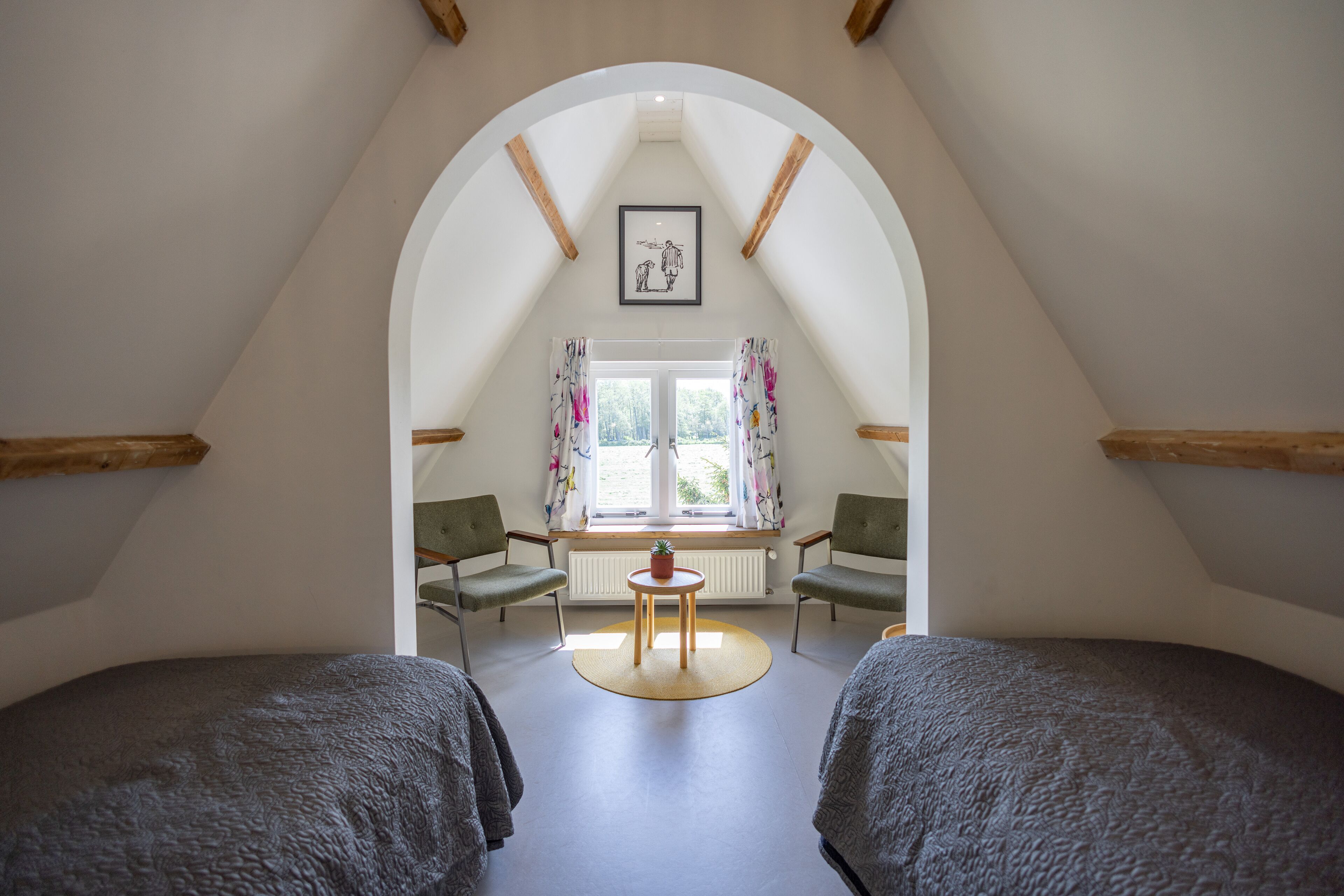 A bedroom with two beds, a small table with a plant, and a window with curtains.