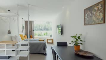 Une chambre d’hôtel moderne, équipée d’un lit, d’un bureau, d’une chaise, d’une plante et d’un tableau au mur.