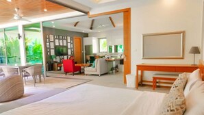 A modern hotel room with a large bed, a dining area, a kitchen, and a living space. - Rawai Ka 3 Bedroom Villa (Rawai)