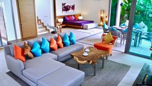 A modern living room with a grey sectional sofa, orange and blue cushions, a wooden coffee table, and a red teapot. - Rawai Ka 3 Bedroom Villa (Rawai)