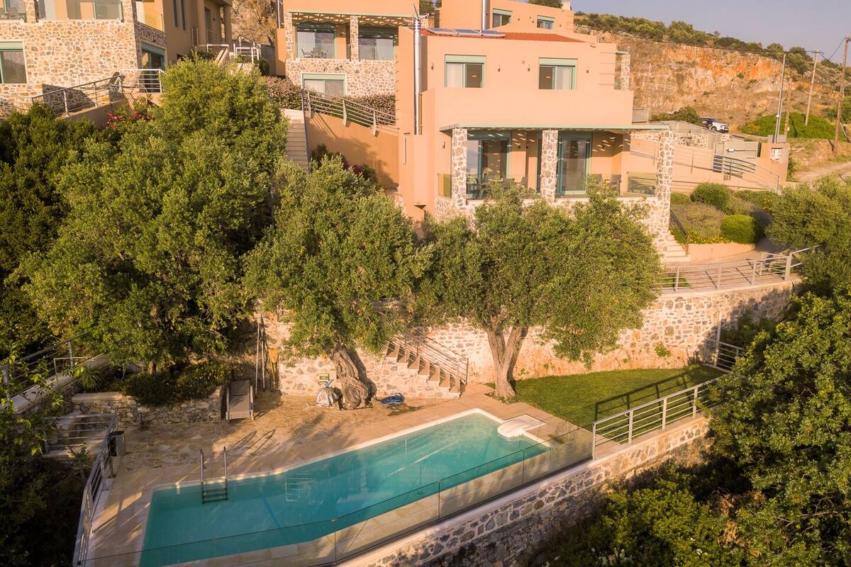 A hillside property with a swimming pool, stone buildings, and lush greenery.