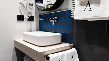 Un baño moderno con un lavamanos blanco, un espejo y un perchero para toallas.