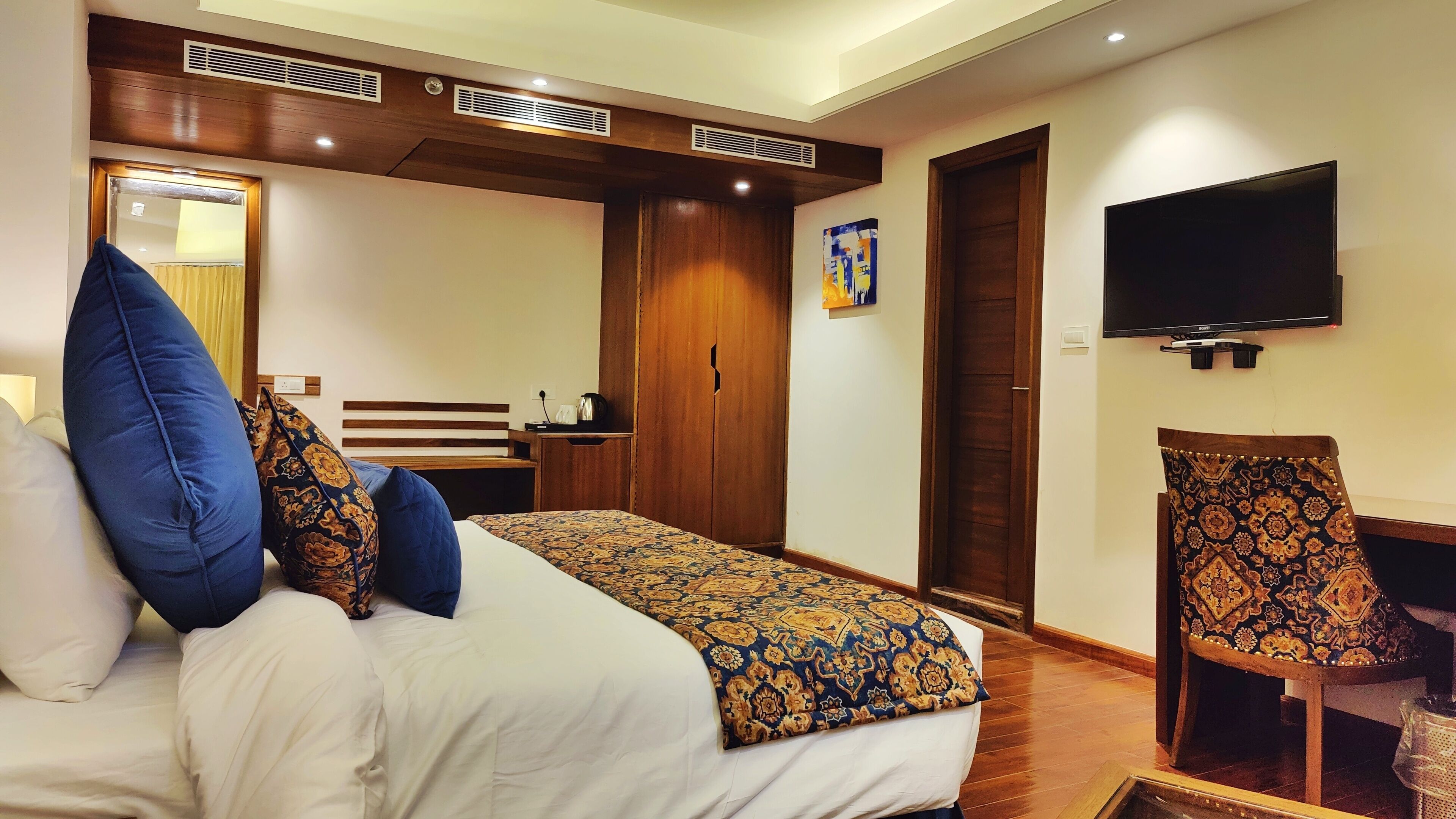 Une chambre d’hôtel avec un grand lit, un bureau, une chaise, une télévision et une armoire.