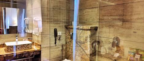 Un baño moderno con ducha envuelta en vidrio, lavamanos con encimera de mármol y retrete.