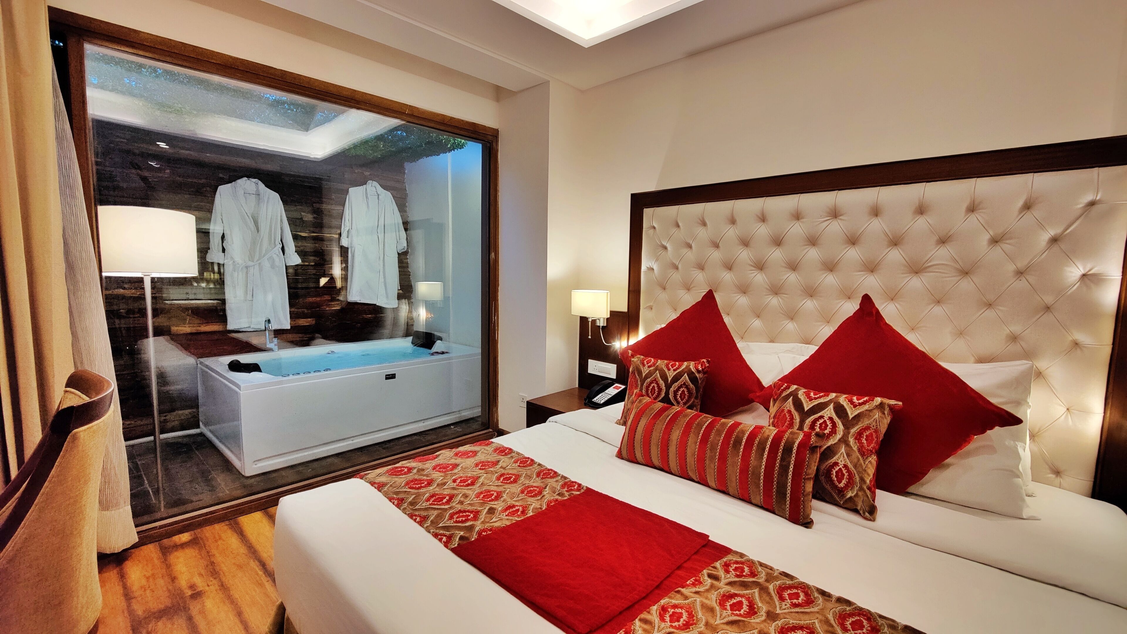 A hotel room with a large bed, a sitting area with a view, and a separate bathroom with a bathtub.