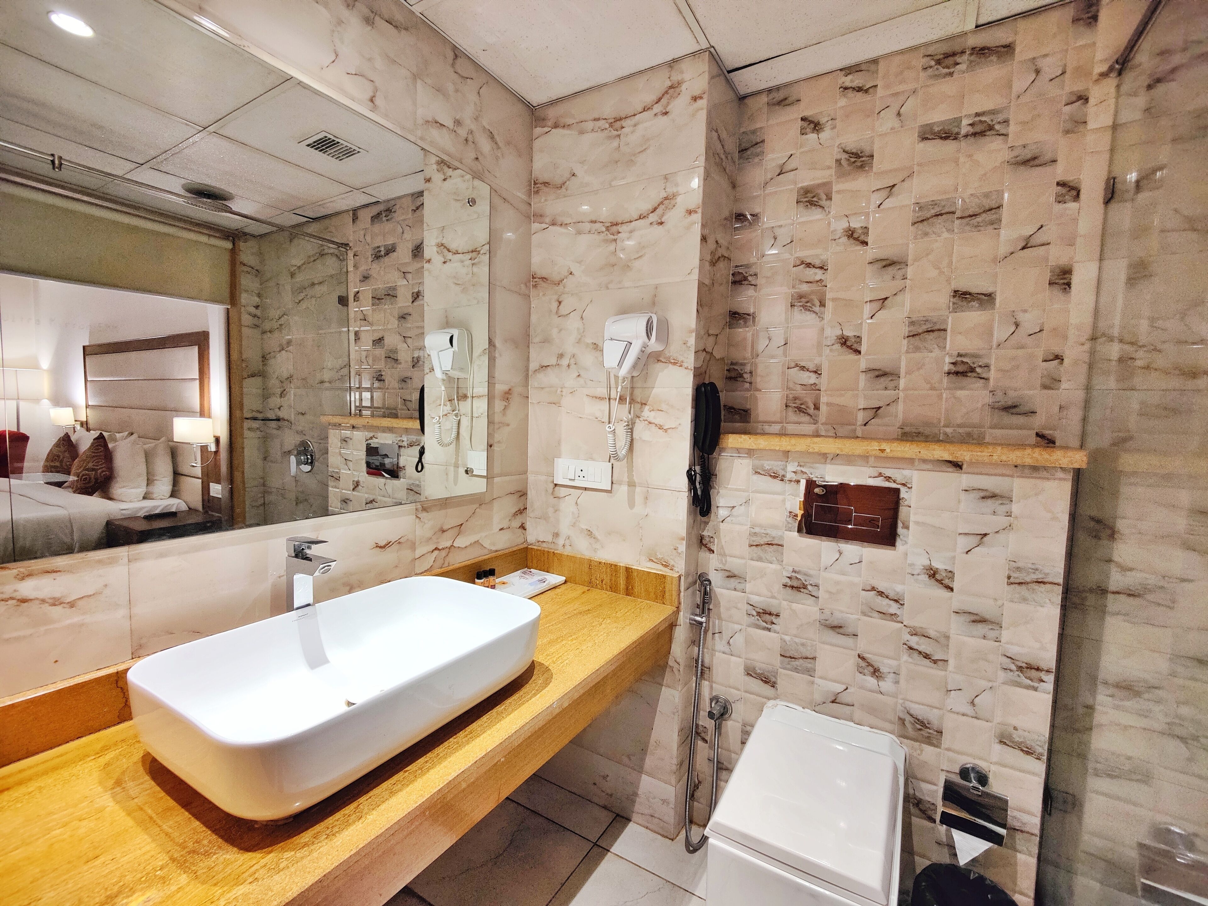 Un baño moderno con un espejo grande, un lavabo blanco y una zona de ducha.