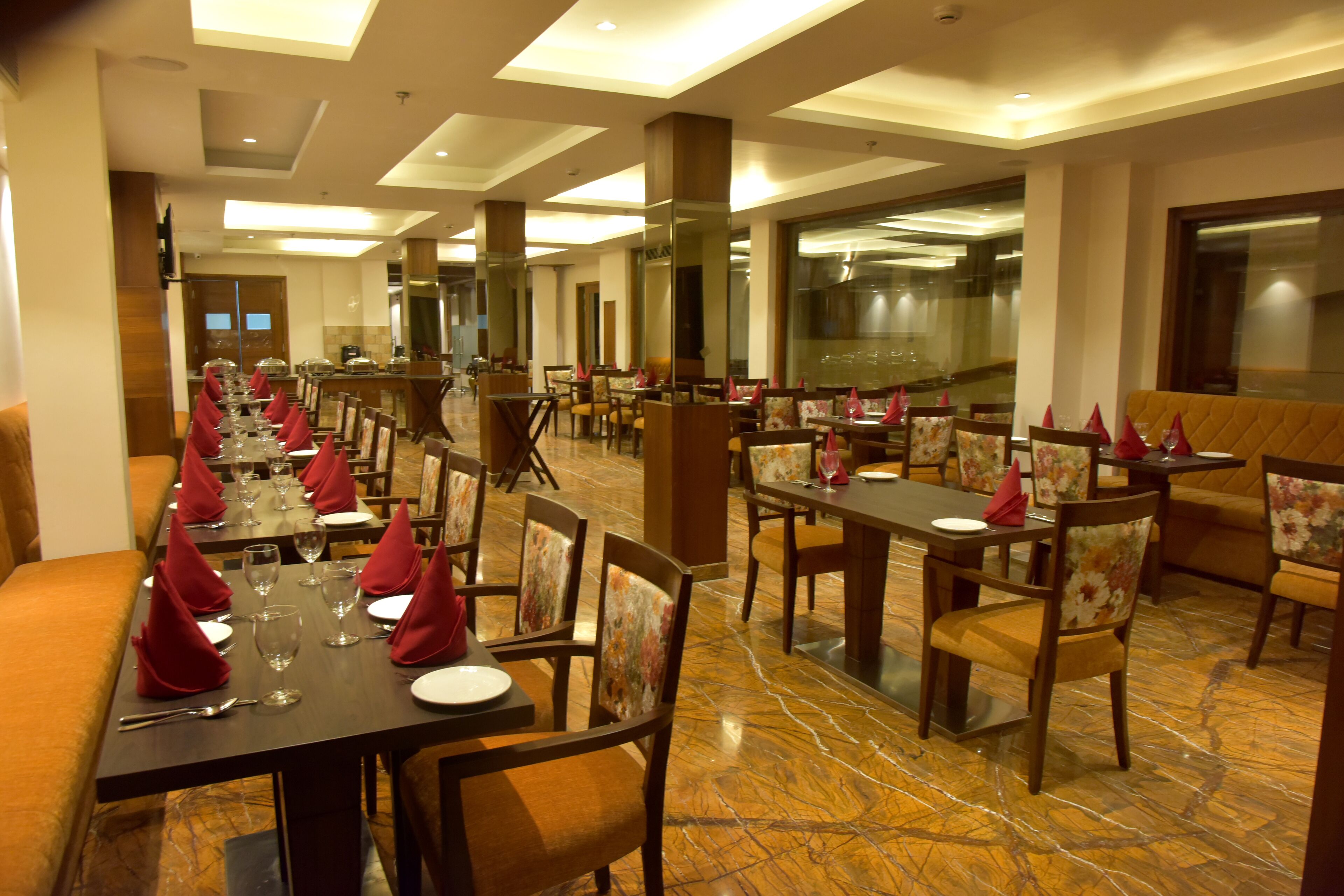 A restaurant with long tables set for dining, featuring a marble floor and wooden chairs.