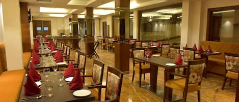 Un restaurante con mesas largas dispuestas para comer, que presenta un suelo de mármol y sillas de madera.